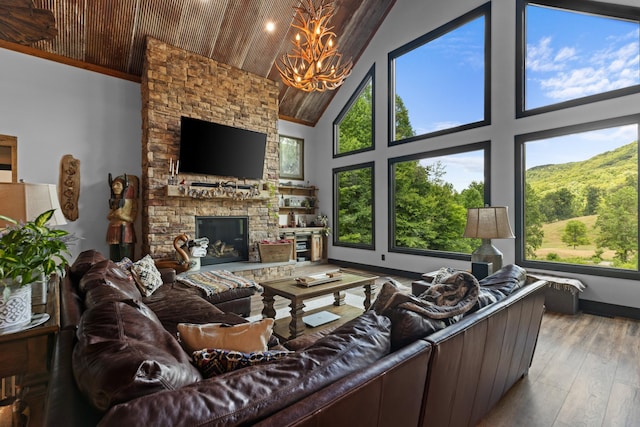 living room with light wood-type flooring, an inviting chandelier, high vaulted ceiling, wooden ceiling, and a stone fireplace