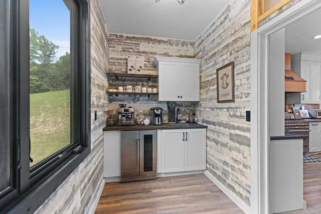 bar with white cabinetry, sink, beverage cooler, and hardwood / wood-style flooring