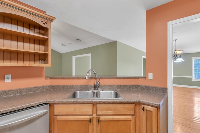 kitchen with a sink, stainless steel dishwasher, wood finished floors, baseboards, and vaulted ceiling