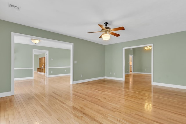 spare room featuring light wood finished floors, visible vents, baseboards, and a ceiling fan