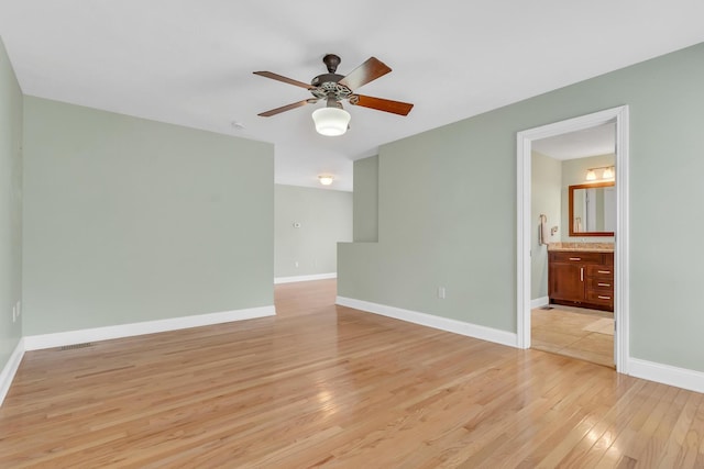 spare room with a ceiling fan, light wood-style floors, and baseboards