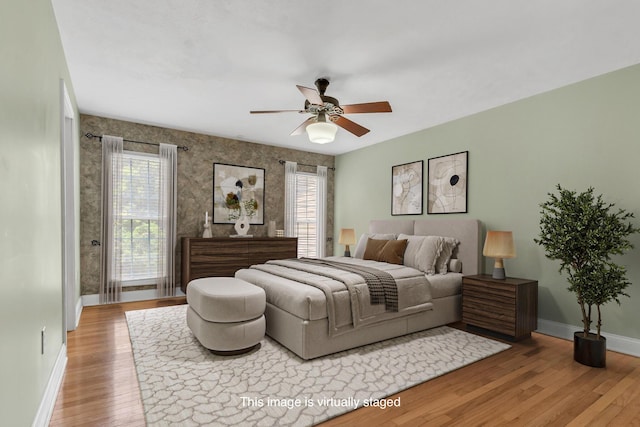 bedroom featuring a ceiling fan, baseboards, and wood-type flooring