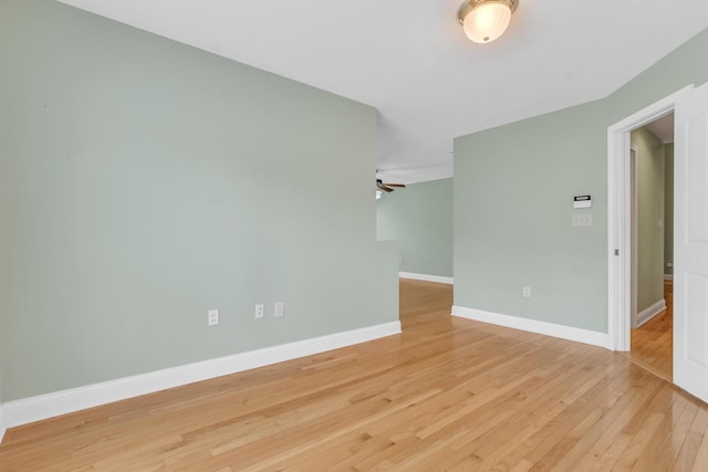 spare room featuring light wood-style flooring, baseboards, and ceiling fan