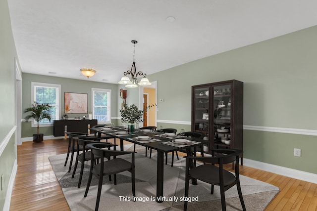 dining room with baseboards, a notable chandelier, and hardwood / wood-style floors