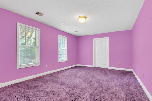 carpeted spare room featuring visible vents and baseboards