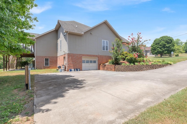 view of side of property with a lawn, stairway, concrete driveway, a garage, and brick siding