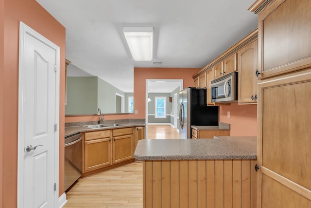 kitchen featuring light wood finished floors, visible vents, appliances with stainless steel finishes, a peninsula, and a sink