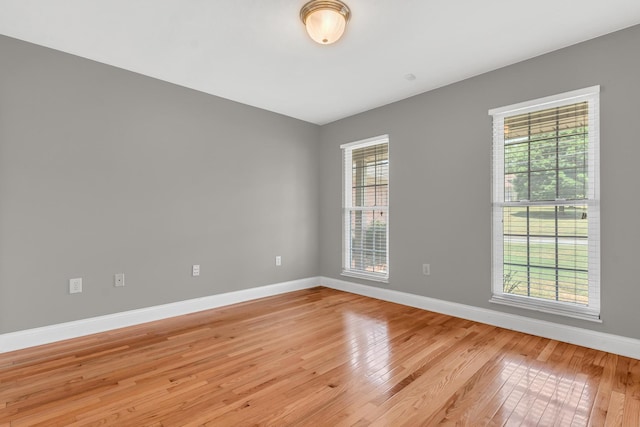 spare room with baseboards and light wood finished floors