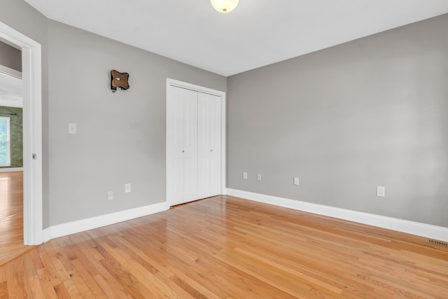 unfurnished bedroom featuring a closet, baseboards, light wood-style floors, and visible vents