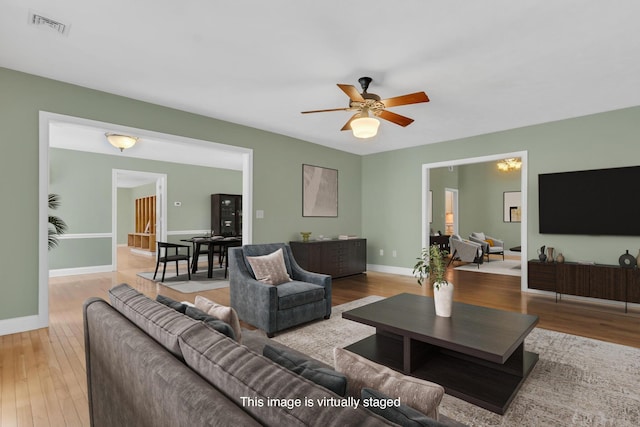 living room with visible vents, baseboards, a ceiling fan, and wood-type flooring