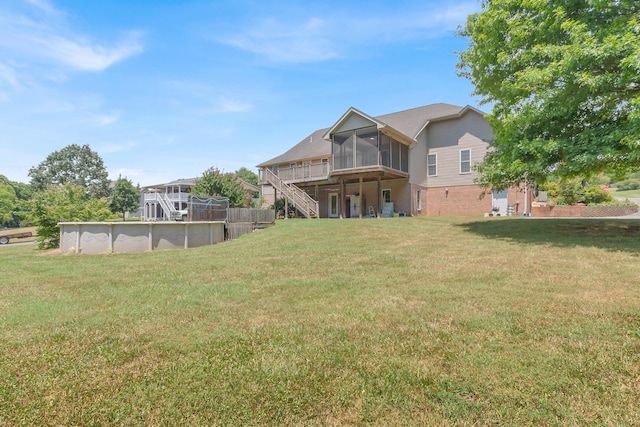 view of yard with an outdoor pool, a wooden deck, stairs, and a sunroom