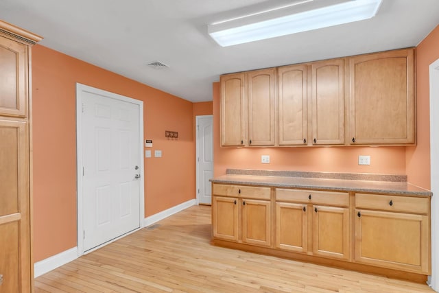 kitchen with light wood-type flooring, visible vents, baseboards, and light brown cabinets