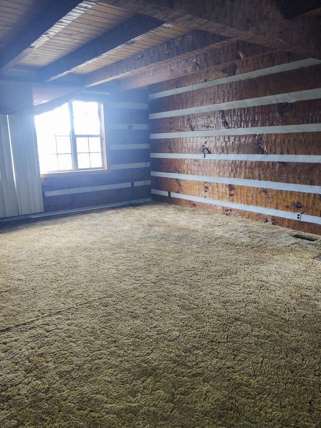 carpeted spare room featuring beam ceiling and wooden ceiling