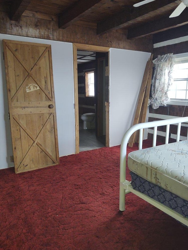 bedroom with carpet, beamed ceiling, ceiling fan, ensuite bath, and wood ceiling