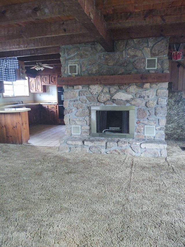 interior space featuring ceiling fan, beamed ceiling, and a fireplace