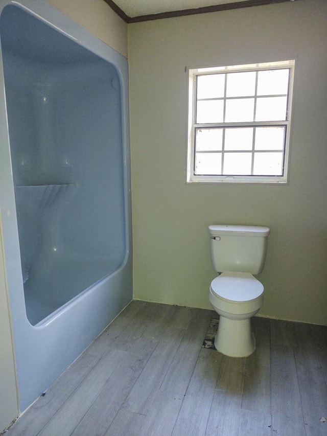 bathroom featuring ornamental molding, a bathing tub, hardwood / wood-style floors, and toilet