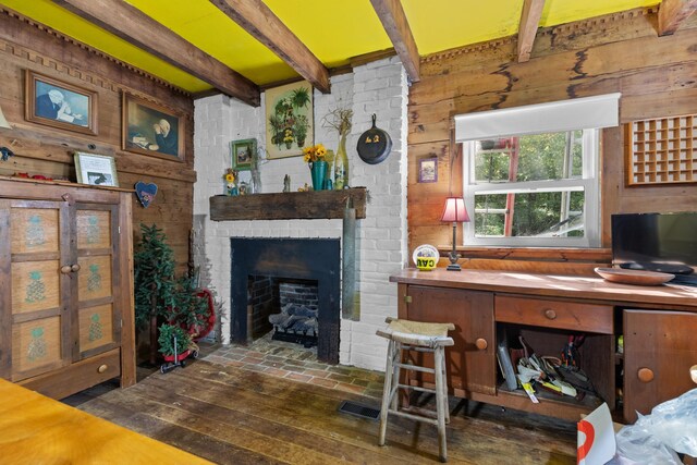 living room featuring wood walls, beam ceiling, dark hardwood / wood-style flooring, and a brick fireplace