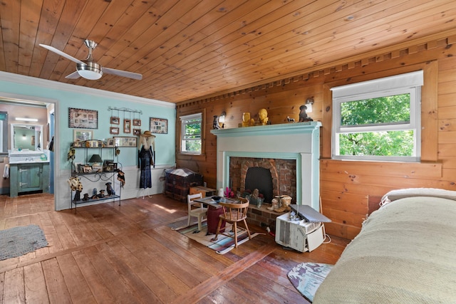 living room featuring wooden ceiling, a brick fireplace, hardwood / wood-style flooring, wooden walls, and ornamental molding