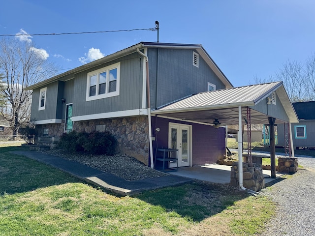 rear view of house featuring ceiling fan, stone siding, french doors, a lawn, and a patio area