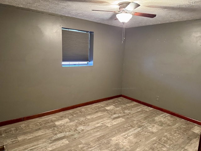 unfurnished room with ceiling fan, a textured ceiling, baseboards, and wood finished floors