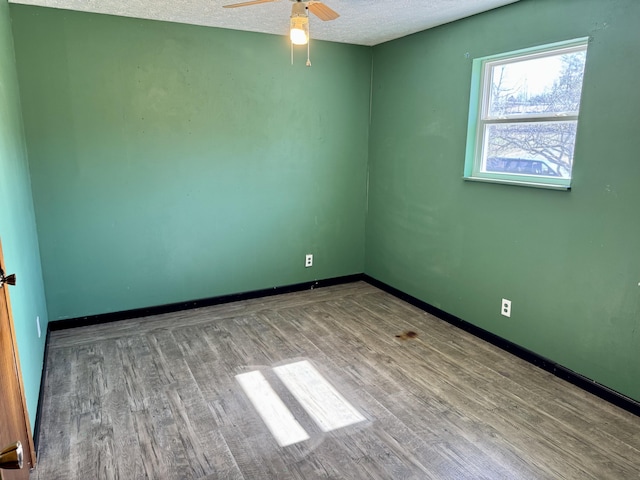 spare room featuring ceiling fan, a textured ceiling, baseboards, and wood finished floors