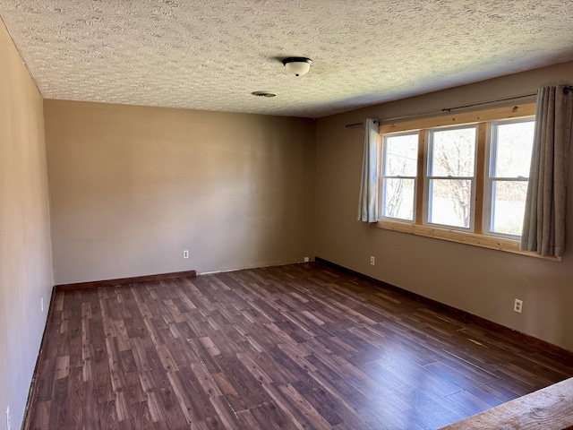 unfurnished room with dark wood-style floors, a textured ceiling, and baseboards