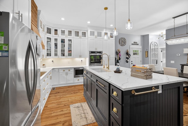 718 Mullins Dr, Sneedville, TN 37869 - kitchen featuring stainless steel appliances, white cabinetry, a kitchen island with sink, light wood-style flooring, and decorative light fixtures