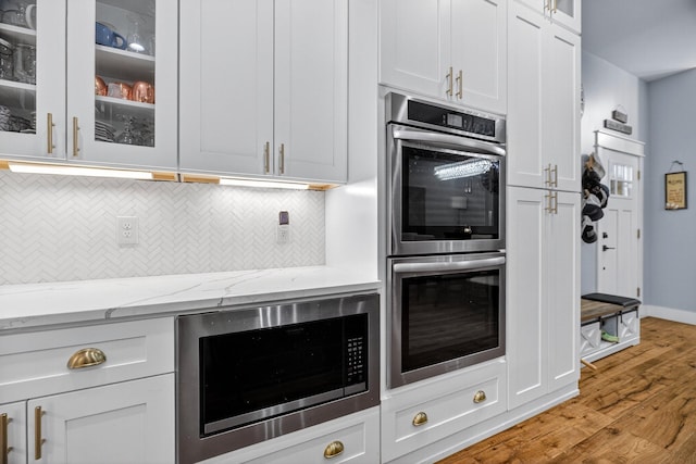 718 Mullins Dr, Sneedville, TN 37869 - kitchen featuring stainless steel appliances, backsplash, light wood finished floors, glass insert cabinets, and light stone counters