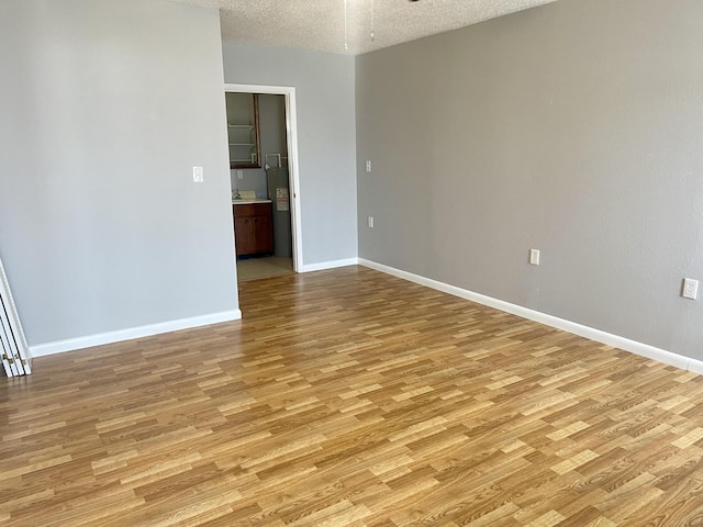 empty room featuring light wood-type flooring and a textured ceiling