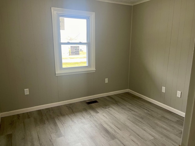 empty room with light hardwood / wood-style floors and crown molding