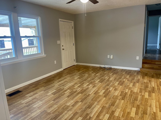 spare room featuring a textured ceiling, light hardwood / wood-style flooring, and ceiling fan