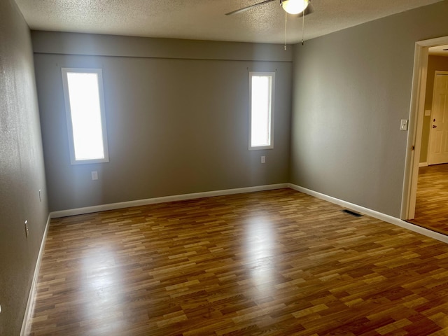 spare room with dark hardwood / wood-style floors, plenty of natural light, and a textured ceiling