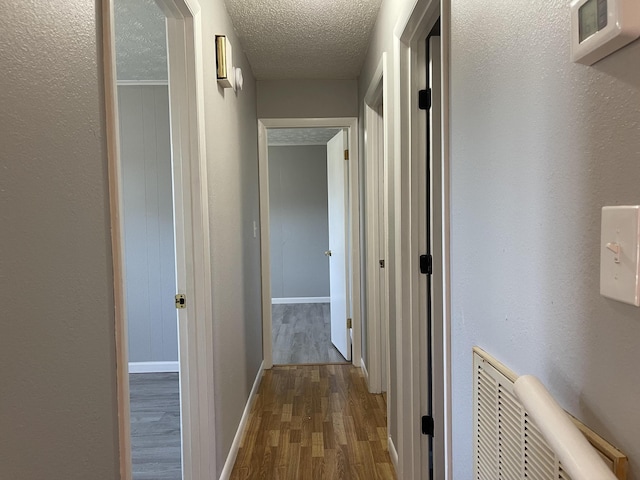 hall with hardwood / wood-style flooring and a textured ceiling