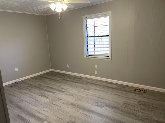 unfurnished room featuring a textured ceiling, ceiling fan, light hardwood / wood-style floors, and crown molding