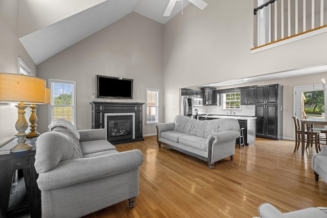 1790 Butterfly Ct, Whitesburg, TN 37891 - living room featuring high vaulted ceiling, a ceiling fan, a glass covered fireplace, plenty of natural light, and light wood-type flooring
