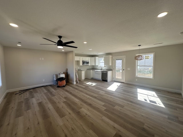 unfurnished living room with ceiling fan, hardwood / wood-style floors, and sink