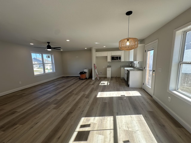 unfurnished living room with plenty of natural light, dark hardwood / wood-style floors, sink, and ceiling fan