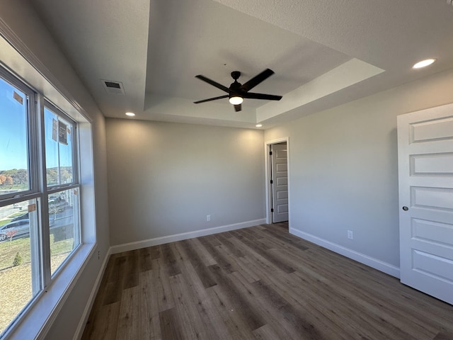 spare room featuring ceiling fan, dark hardwood / wood-style flooring, and a tray ceiling