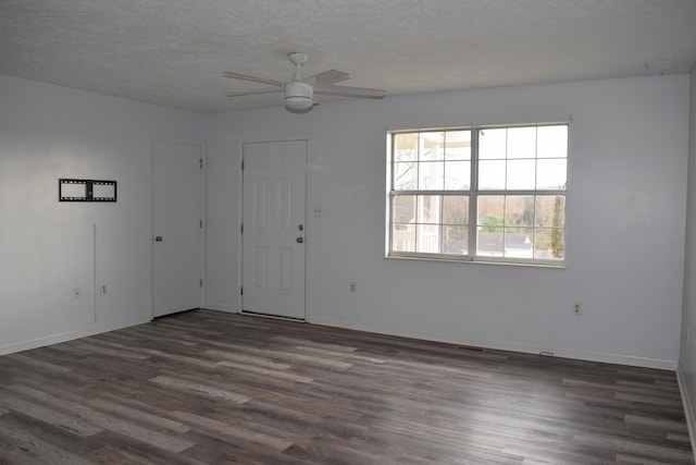 spare room featuring dark wood finished floors, a textured ceiling, and baseboards