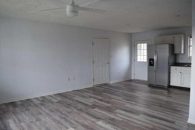 interior space featuring a wealth of natural light, baseboards, wood finished floors, and a textured ceiling