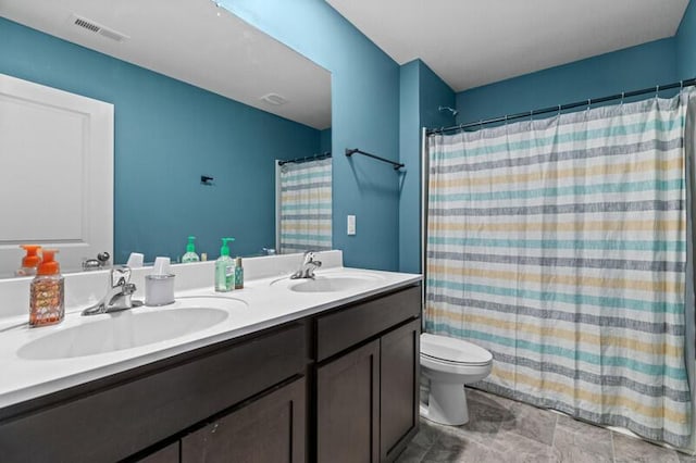 bathroom featuring visible vents, a sink, double vanity, and toilet