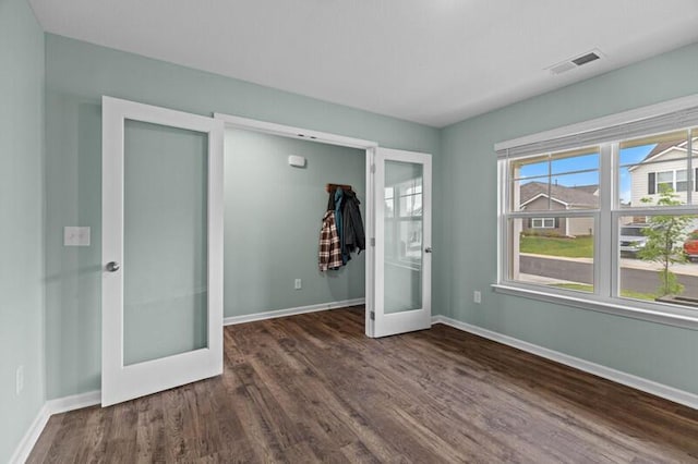empty room featuring baseboards, french doors, dark wood finished floors, and visible vents
