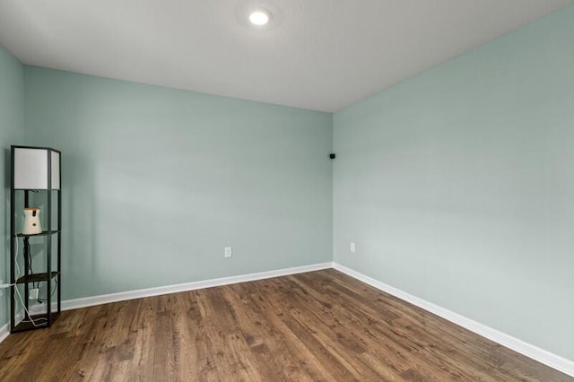 empty room featuring baseboards and dark wood-style flooring