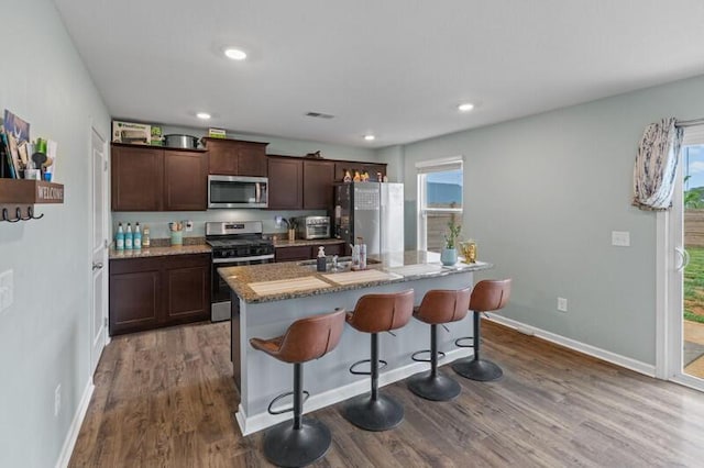 kitchen featuring a breakfast bar area, a kitchen island, visible vents, appliances with stainless steel finishes, and dark wood finished floors