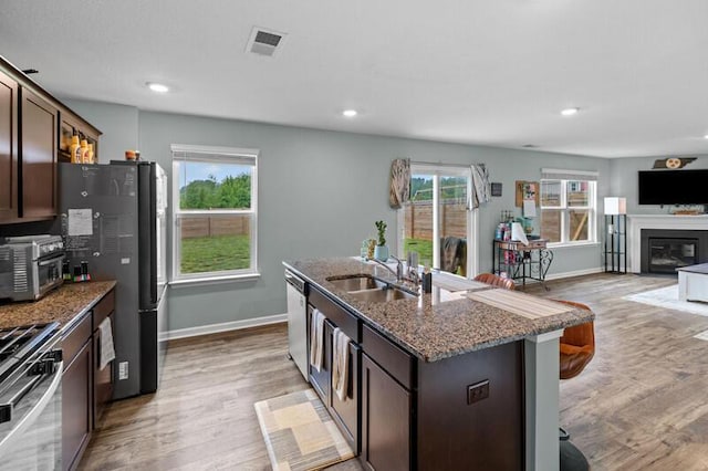 kitchen with a sink, stainless steel appliances, light wood-style flooring, and visible vents