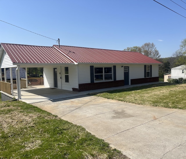 ranch-style home featuring concrete driveway, a front lawn, an attached carport, metal roof, and brick siding