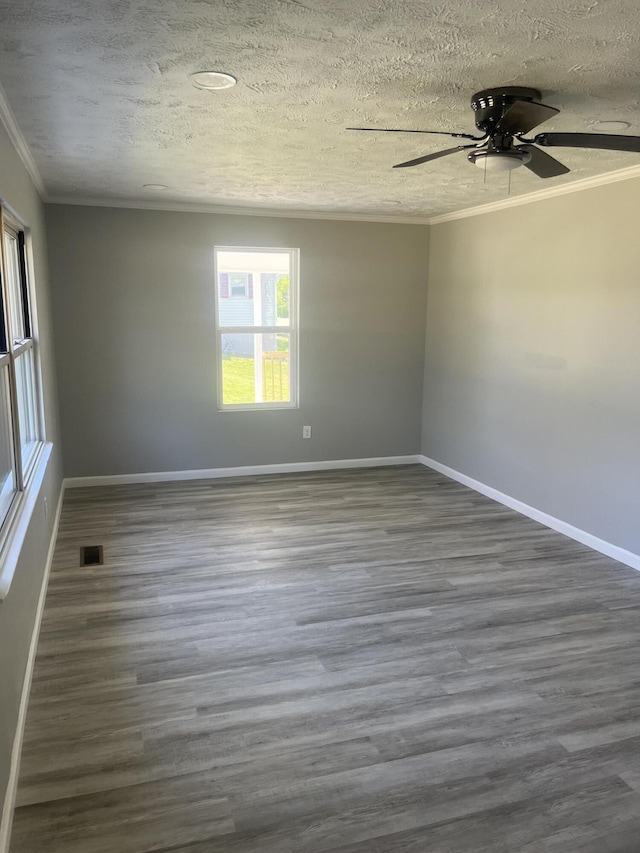 spare room with dark wood finished floors, a textured ceiling, crown molding, visible vents, and ceiling fan