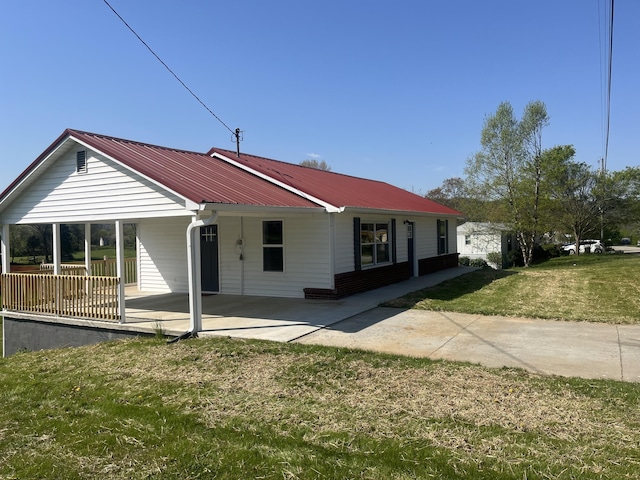 view of front of house featuring a patio area, a front yard, and metal roof