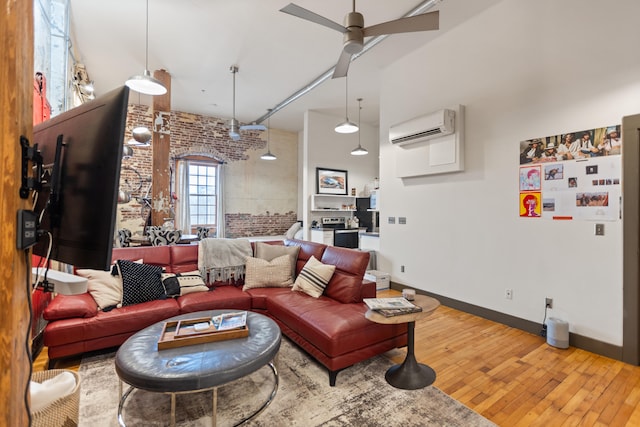 living room featuring baseboards, brick wall, ceiling fan, hardwood / wood-style floors, and a wall mounted air conditioner