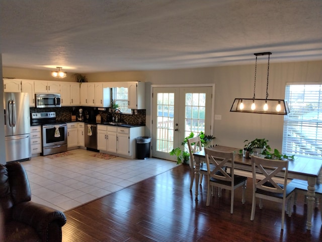 kitchen featuring white cabinetry, sink, backsplash, decorative light fixtures, and appliances with stainless steel finishes